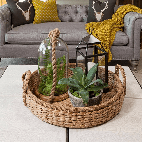 A basket tray with a terrarium, a candle lantern and a potted plant for a boho chic feel
