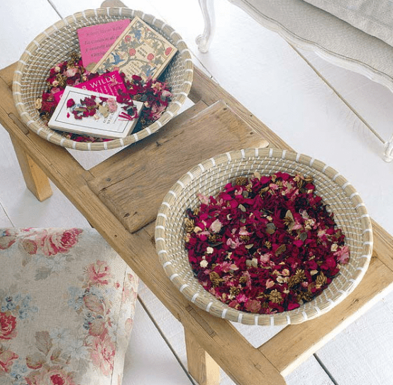 a wooden coffee table with baskets filled with colorful petals and some books is a very dreamy idea