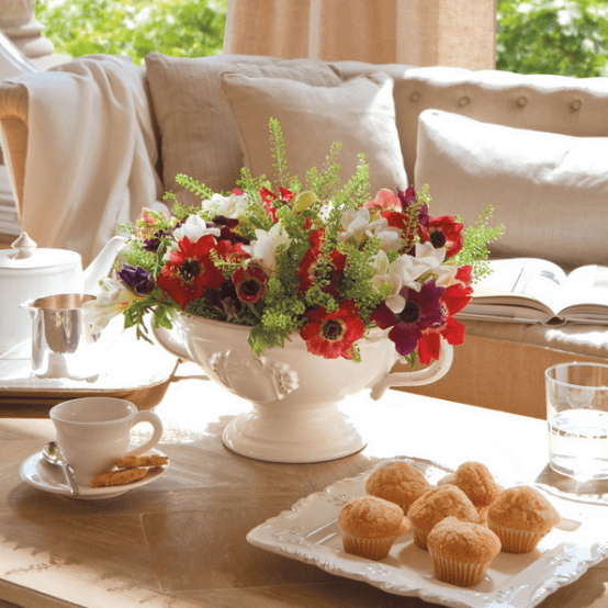 beautiful coffee table styling with a bright floral centerpiece, coffeeware and tasty cupcakes