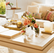 a contemporary coffee table with some fresh blooms, books, a candle and fresh wine