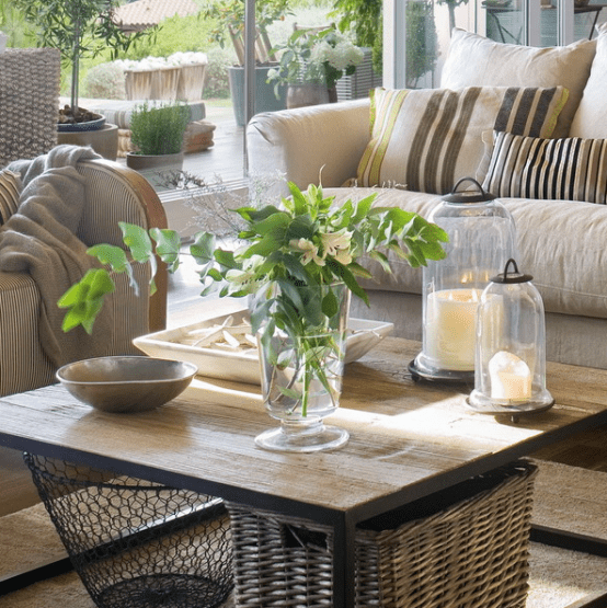 a wooden coffee table with candle lanterns, a greenery and floral arrangement, a tray with starfish for a coastal feel