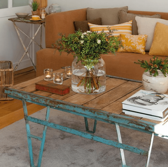 a shabby chic coffee table with a wooden top, fresh greenery and blooms and just some candles