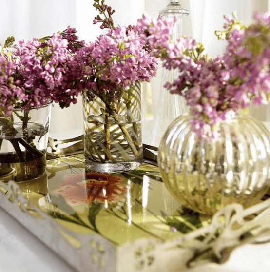 a coffee table with a tray and bright floral arrangements in clear vases is a very chic and cool idea