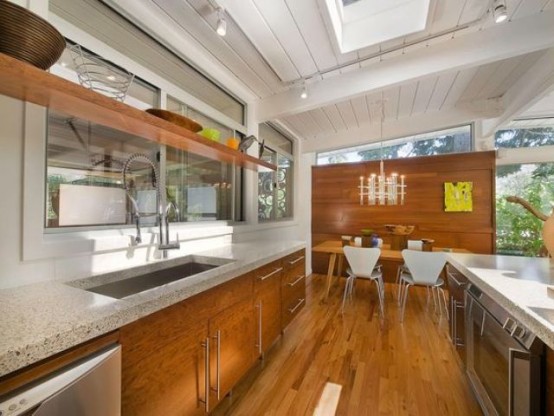a mid-century modern kitchen wooden cabinets and stone countertops, w indow backsplash and skylights for more natural light