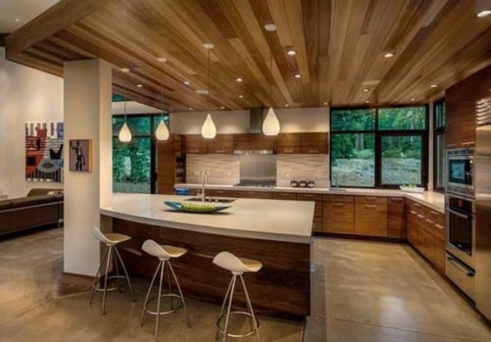 a mid-century modern kitchen with wooden cabinets and neutral countertops, white stools and pendant lights
