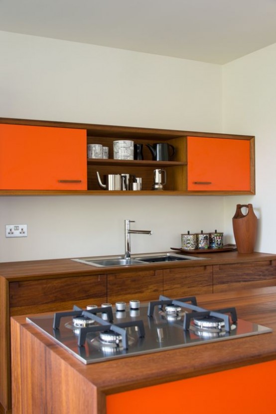 a mid-century modern kitchen with rich-stained wood and bright orange cabinets, metal appliances