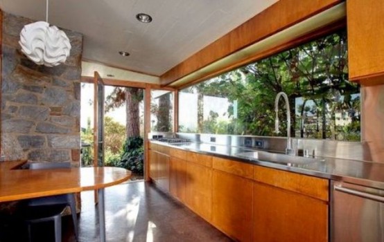 an orange mid-century modern wooden kitchen with metal countertops, a window backsplash and a matching table