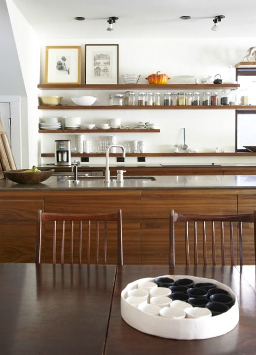 a mid-century modern kitchen with no uppers, open shelving, a large kitchen island and artworks