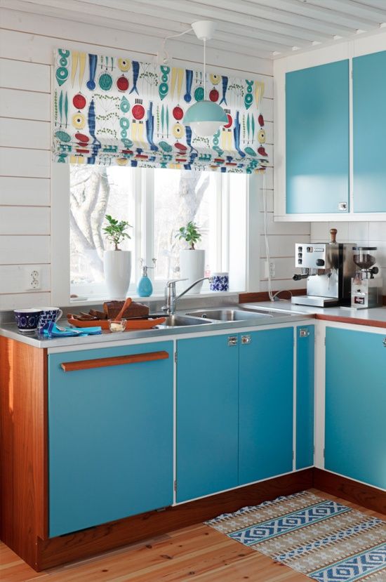 a bright blue mid-century modern kitchen with colorful Roman shades, touches of rich stained wood