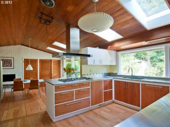 a bright mid-century modern kitchen with wooden cabinets, white countertops, skylights and a window backsplash