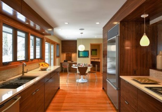 a rich-stained mid-century modern kitchen with white countertops and pendant lamps 