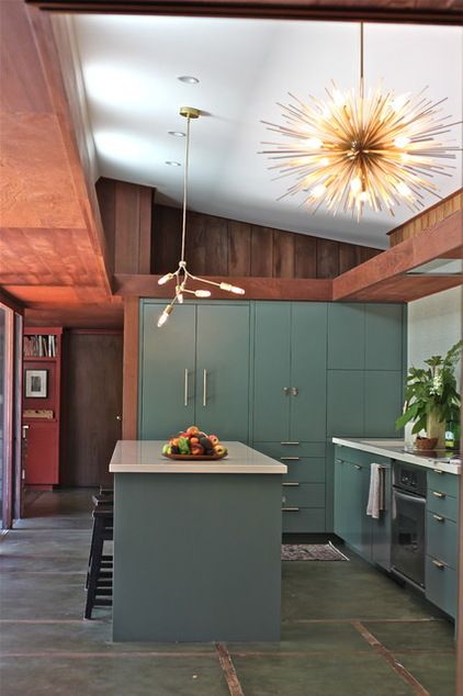 a green mid-century modern kitchen with catchy lamps and white countertops