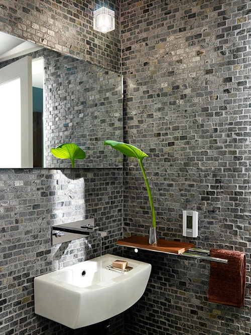 a bathroom or a powder room with grey brick walls, a curved sink, a mirror and a modern mini shelf