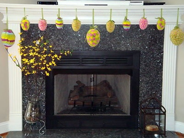 Colorful paper Easter eggs hanging on the mantel and blooming branches in vases