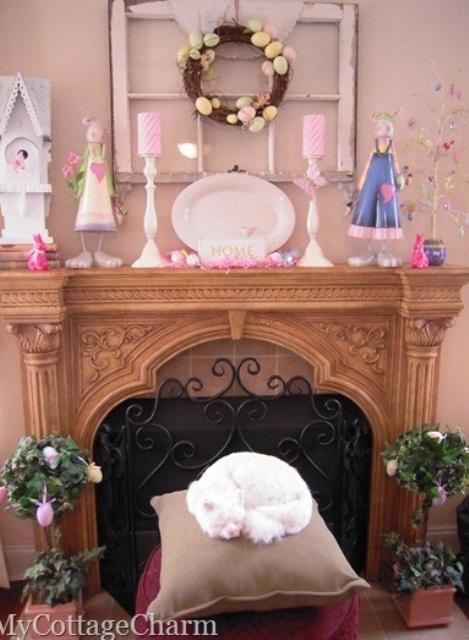 a funny Easter mantel a fake bird house, colorful candles, an Easter tree and an egg wreath