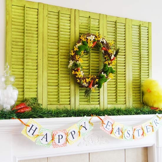 a bright Easter mantel with green shutters, some grass, carrots, a toy chick and a bunting