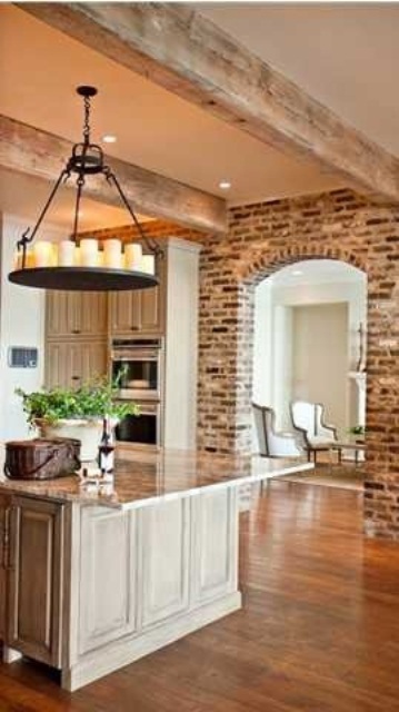 distressed brick walls and wooden beams on the ceiling bring texture and interest to the kitchen making it more rustic