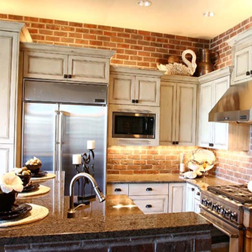A red brick wall paired with neutral vintage cabinets make up a cool vintage inspired kitchen