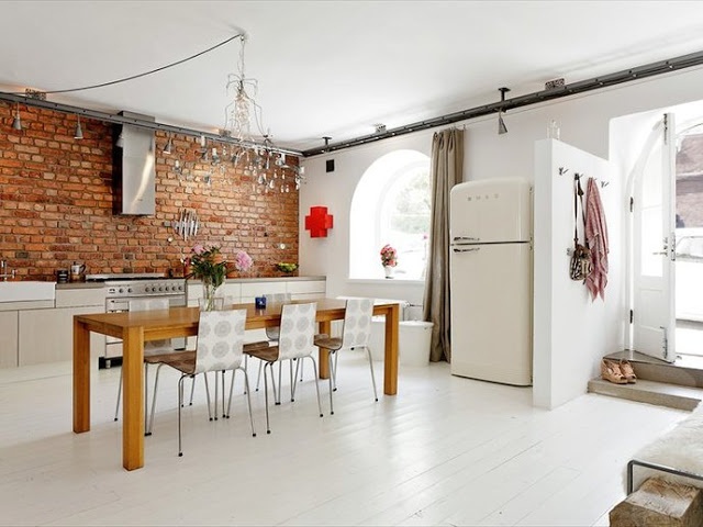 A bright white kitchen is spruced up with a red brick wall that adds interest to the space and makes it more color filled