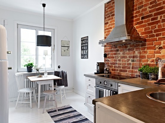 an all-white kitchen with a red brick cooker backsplash that adds interest, color and even character to the space