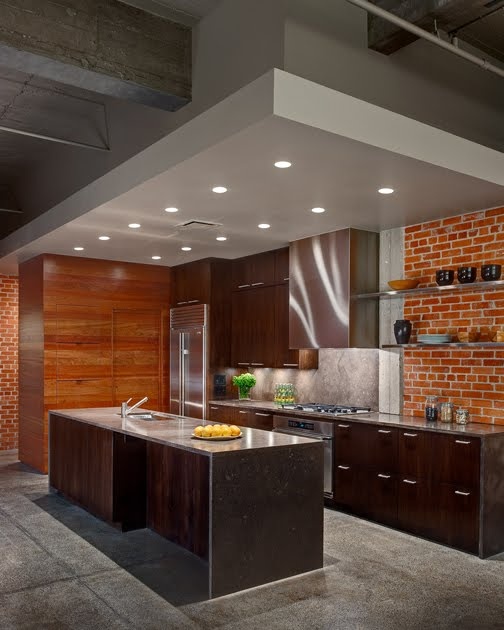 a dark modern kitchen with a red brick wall and rich stained wooden furniture for a catchy and bold look