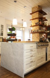 a brick pillar with wooden shelves is a catchy decor element that adds texture and storage space to the kitchen