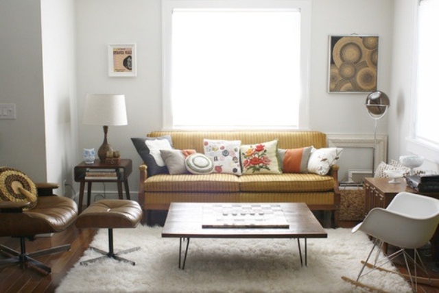 A neutral living room with mid century modern furniture, artworks and a leather chair plus bright pillows