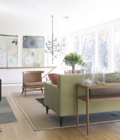 a pastel mid-century modern living room with pastel green and beige furniture, artworks and a chandelier