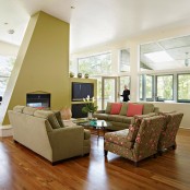 a bright mid-century modern living room done in green, with floral chairs, a built-in fireplace and TV