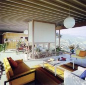 a neutral mid-century modern living room with yellow furniture, lots of greenery and a large panoramic view