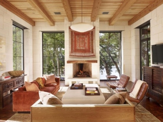 a cozy neutral and brown living room with wooden beams and a ceiling, leather chairs, dark and light stained furniture
