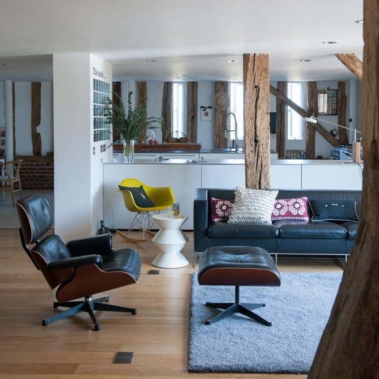 a mid-century modern meets rustic living room with black leather furniture, wooden beams and bright  touches