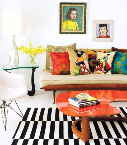 A bright mid century modern living room with elegant furniture, bright artworks, colorful and printed pillows