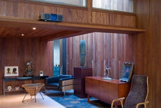 a cozy mid-century modern living space with stained wood that covers everything, stylish furniture and artworks