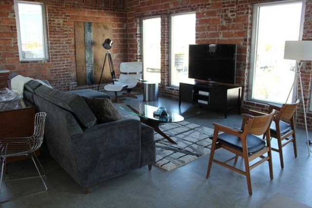An industrial space with brick walls and elegant mid century modern furniture plus lamps