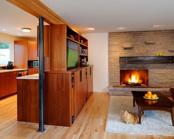 A welcoming living room with a faux stone wall, a built in fireplace, a stained wooden furniture unit and fluffy rugs