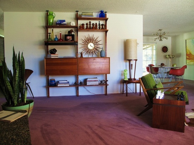 A mid century modern space with a mauve rug, dark staiend furniture and potted plants
