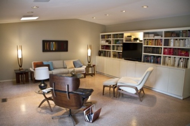 A white mid century modern living room with a built in bookcase, cremay furniture, elegant lamps and a chic artwork