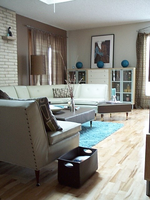 a neutral living room spruced up with blue and brown touches, with some prints and faux brick plus artworks