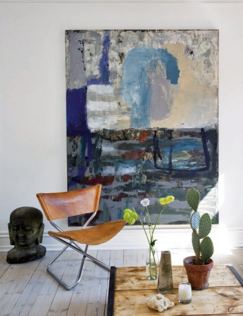 a fantastic nook with a leather butterfly chair, a statement artwork, potted cacti and natural light