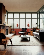 a mid-century modern living room with bright orange and yellow touches, dark touches, faux brick, plywood and cork touches