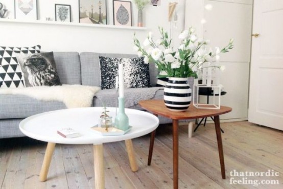 a duo of Scandinavian coffee tables - a small round white one and a triangle-shaped rich-stained coffee table