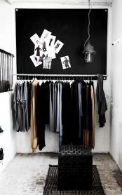 a minimalist meets industrial closet with a pendant lamp, a leather ottoman and a clother hanger holder