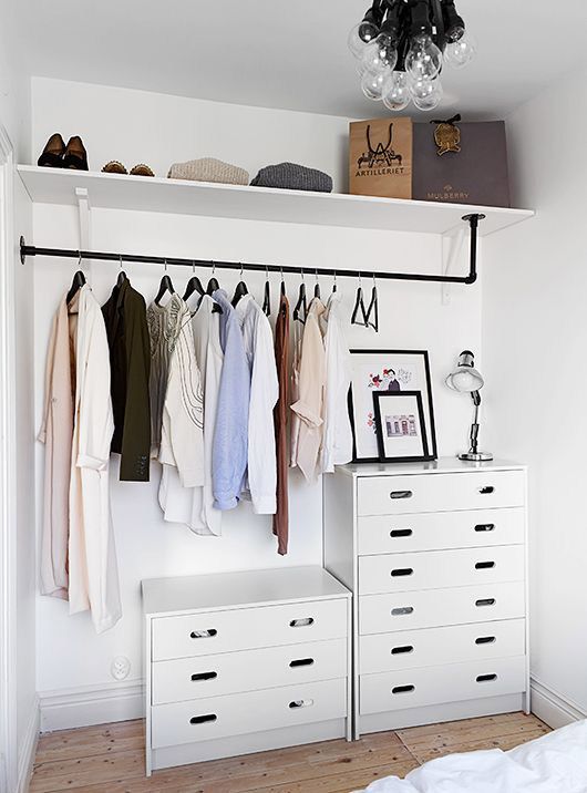 a minimalist closet in white with an open shelf, a makeshift closet and a couple of dressers