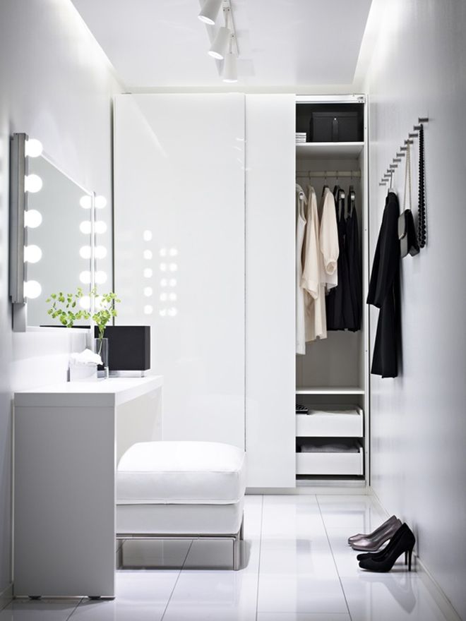 An ultra minimalist closet in white with a storage unit with sliding doors, some drawers, a comfy makeup unit