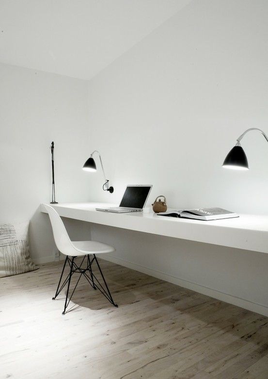 a clean minimalist home office with a floating desk, a white chair and black sconces is a stylish space for comfortable working