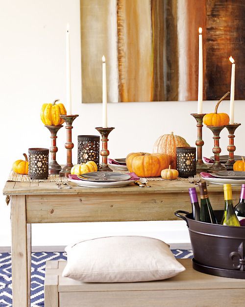 a modern Moroccan tablescape with cutout candleholders, pumpkins, candles, a woven table runner