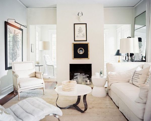 A refined neutral living room with a built in fireplace, neutral refined furniture, chic artworks and mirrors in ornated frames and neutral textiles is amazing