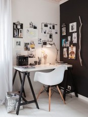 a small Scandi home office nook in black and white, with a trestle desk, a white chair, a gallery wlal, some lights and lamps is a lovely and cool space