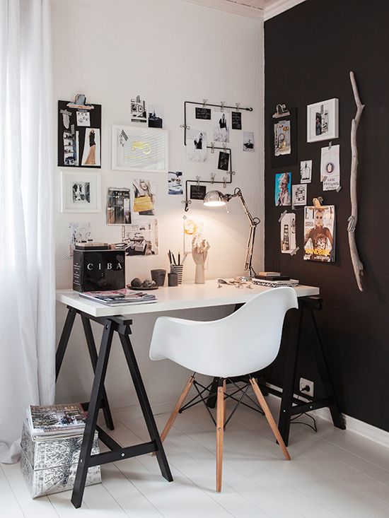 a small Scandi home office nook in black and white, with a trestle desk, a white chair, a gallery wlal, some lights and lamps is a lovely and cool space